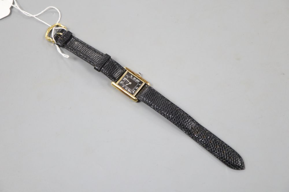 A ladys 925 gilt Must De Cartier manual wind wrist watch, with rectangular black Roman dial, on Cartier strap,